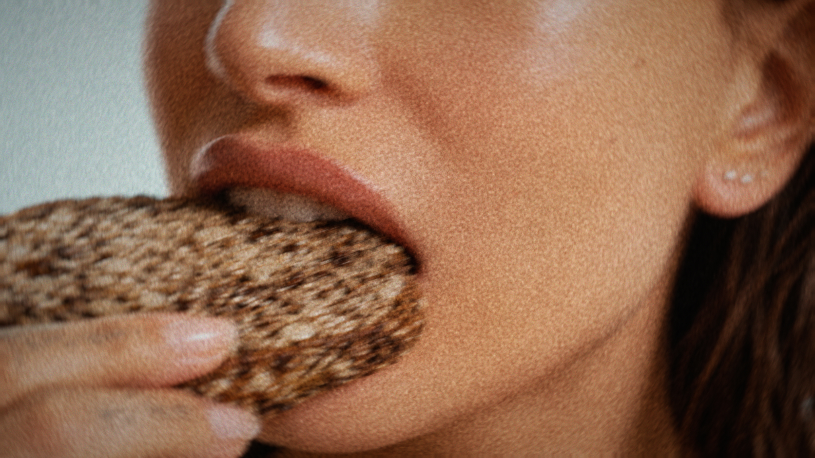 Close crop of a mouth biting into a slice of seed bread